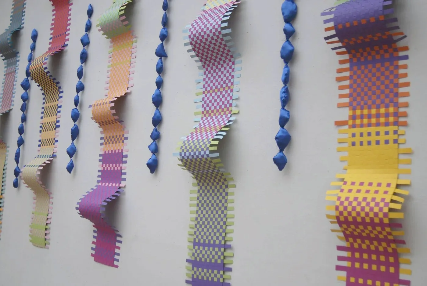 Detail of the patterned woven surfaces and suspended blue forms in Flow
