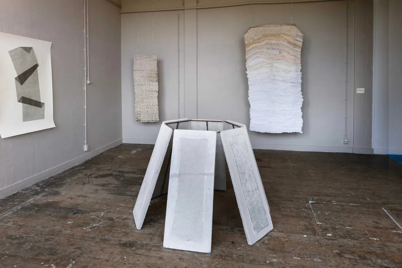 Installation with sculptural panels and hanging textile works