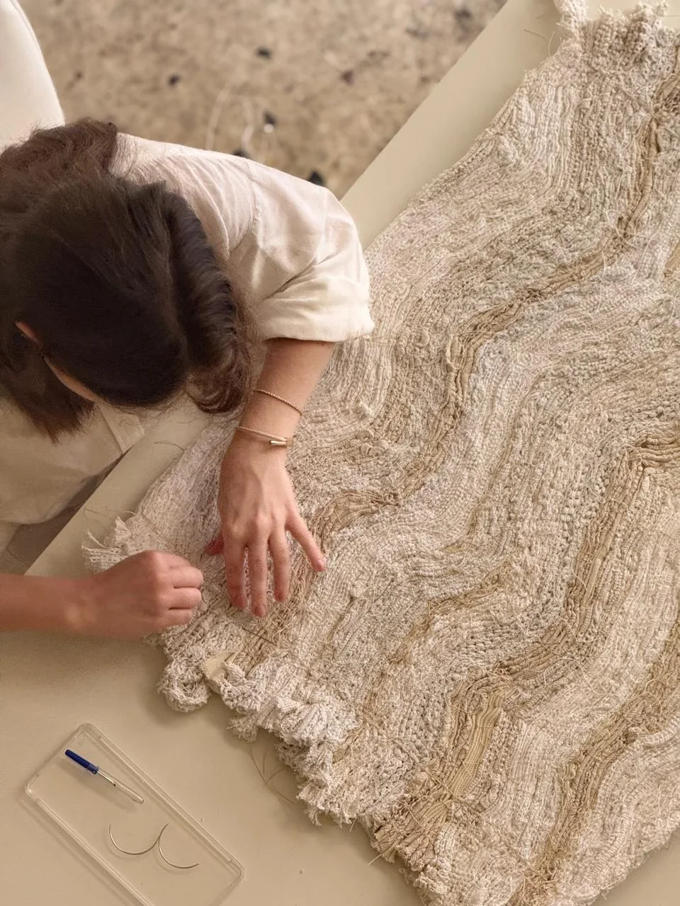 Hara working by hand on a layered textile at a studio table