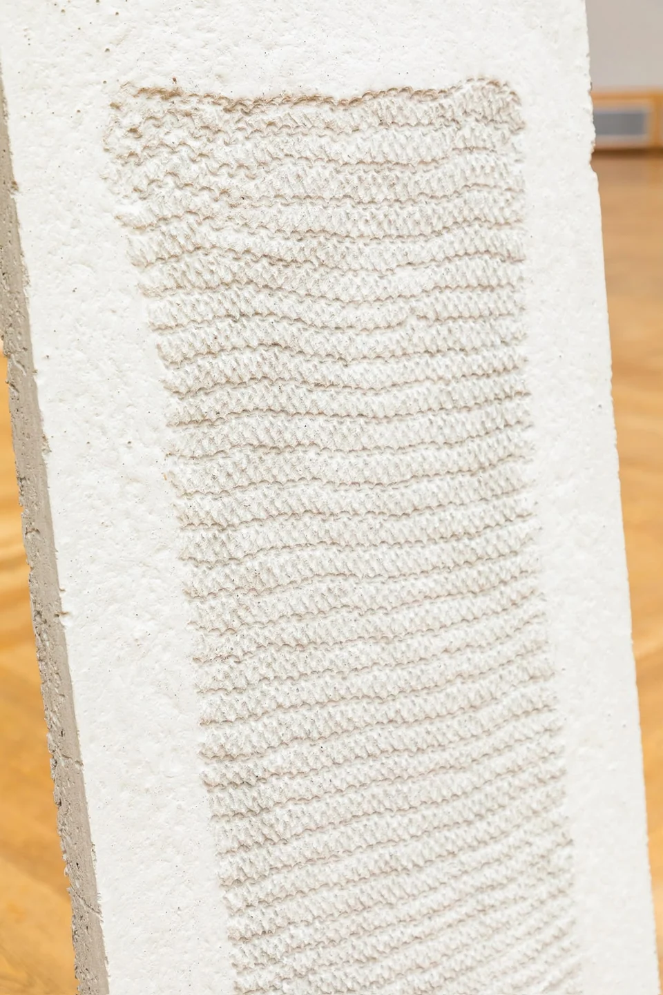 Pale sculptural panel with an impressed textile pattern