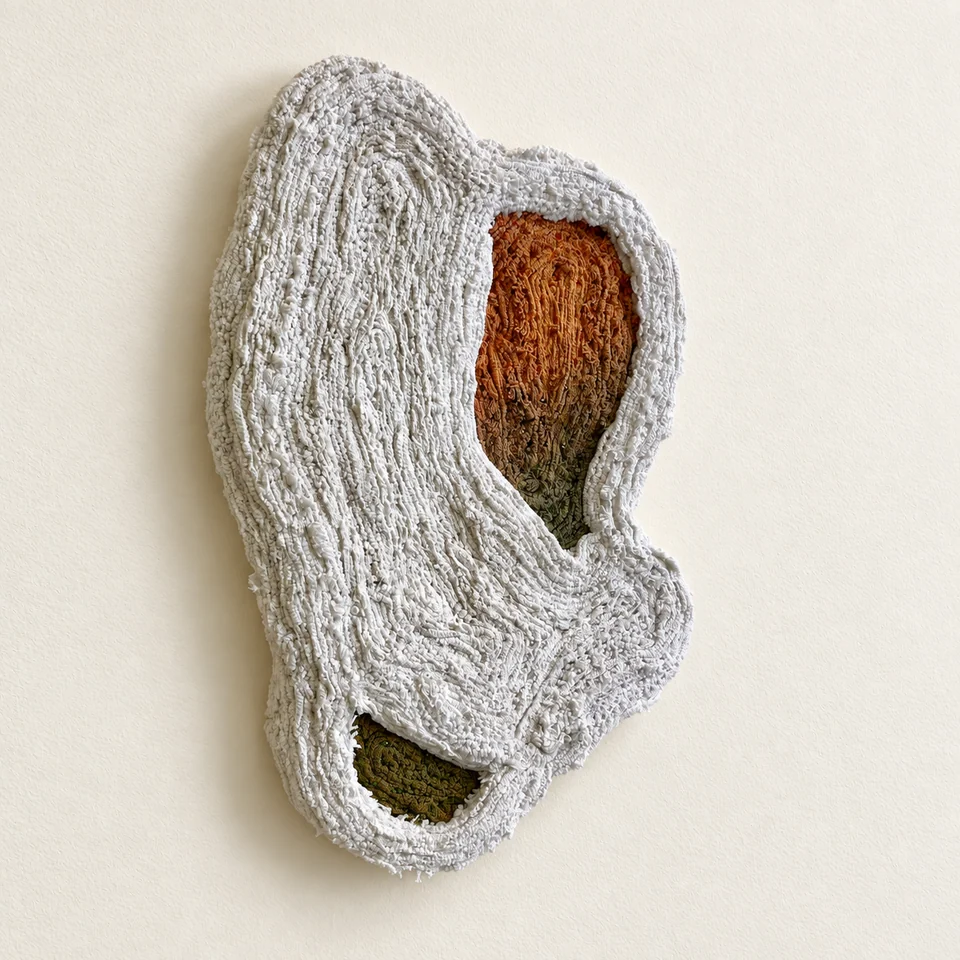 Layered white textile with ochre and green openings