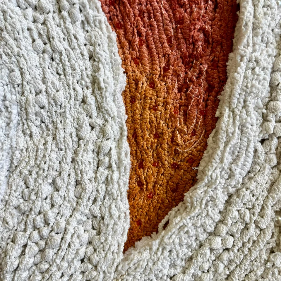 Detail of Threaded Keep showing white lace surrounding red and ochre fibres with beads