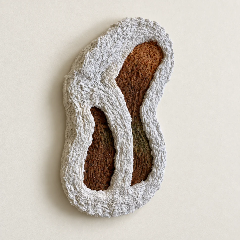 Soft Chamber by Hara Athanasopoulou, white textile surrounding ochre and olive fibres against an ivory wall